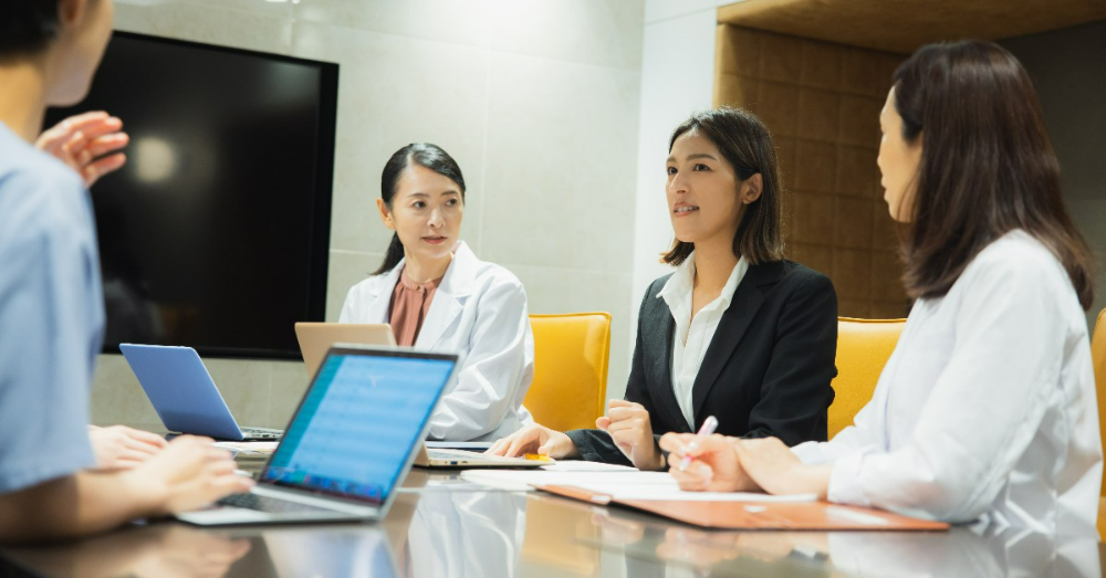 医師と打ち合わせをするスーツの女性